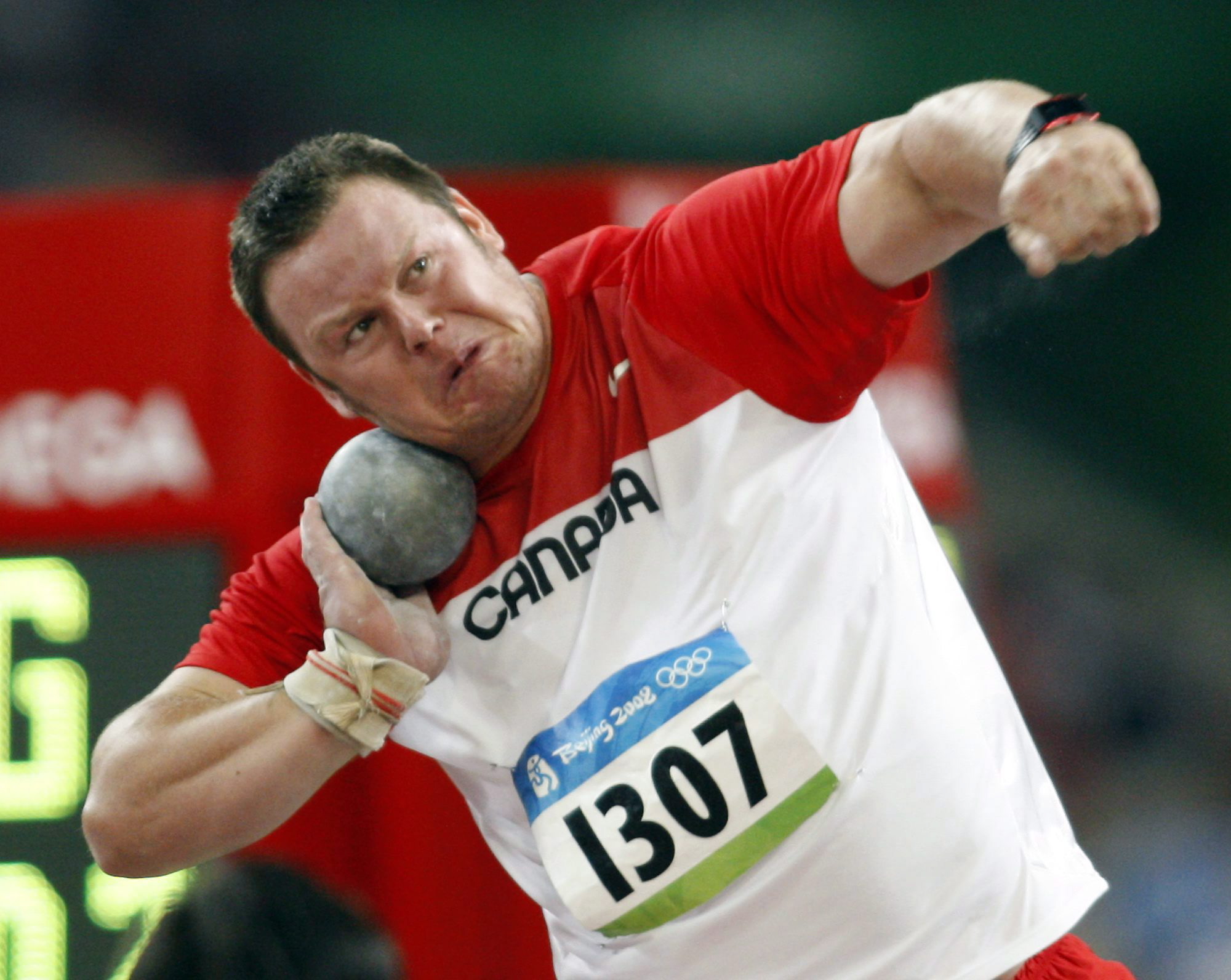 Dylan Armstrong amorce un lancer du poids, le poids contre son visage.
