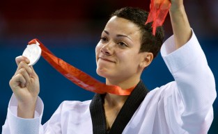 Karine Sergerie tient sa médaille d'argent dans la main droite en saluant la foule.