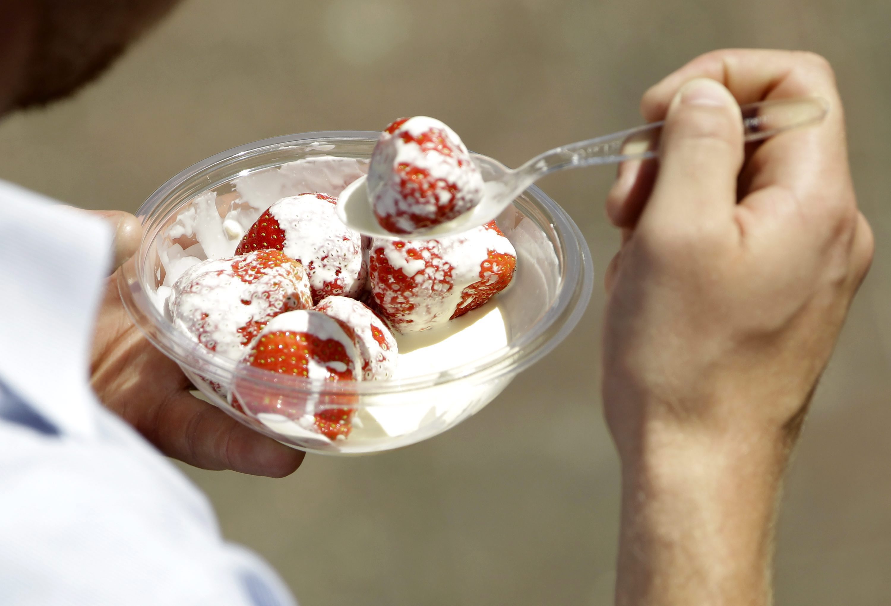 Un spectateur mange des fraises à la crème pendant le tournoi de Wimbledon, le jeudi 23 juin 2011. (AP Photo/Sang Tan)