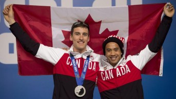 Gilmore Junio posant avec Denny Morrison, tenant le drapeau canadien