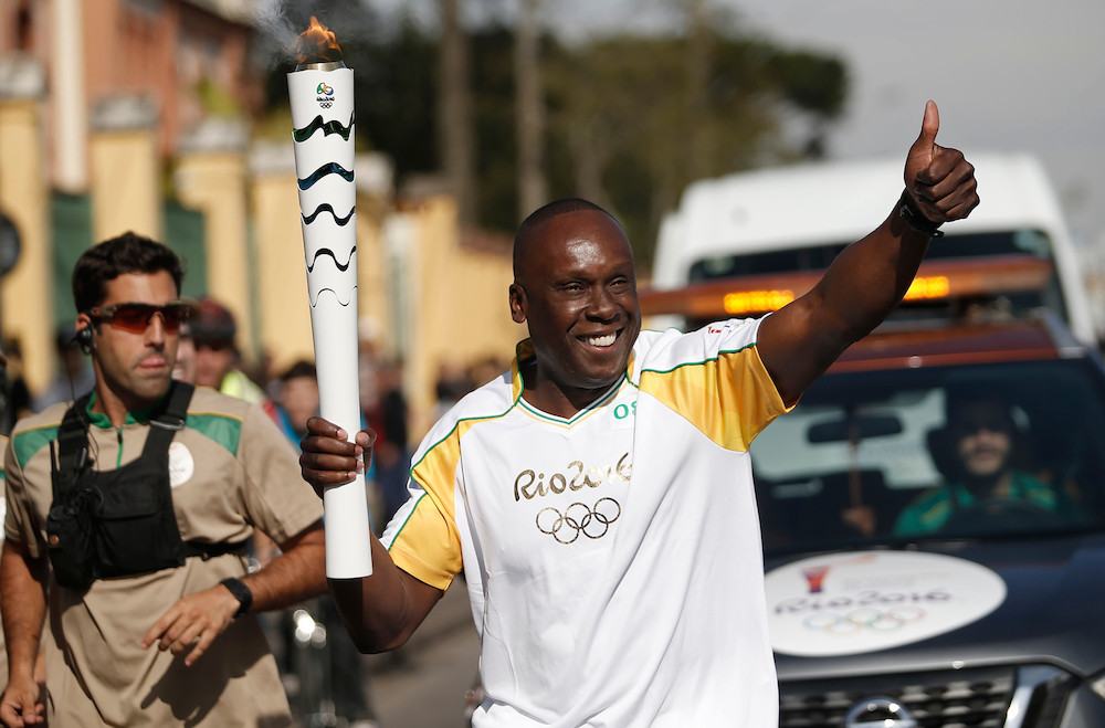 Bruni Surin court avec la flamme olympique avant les Jeux olympiques de Rio 2016.