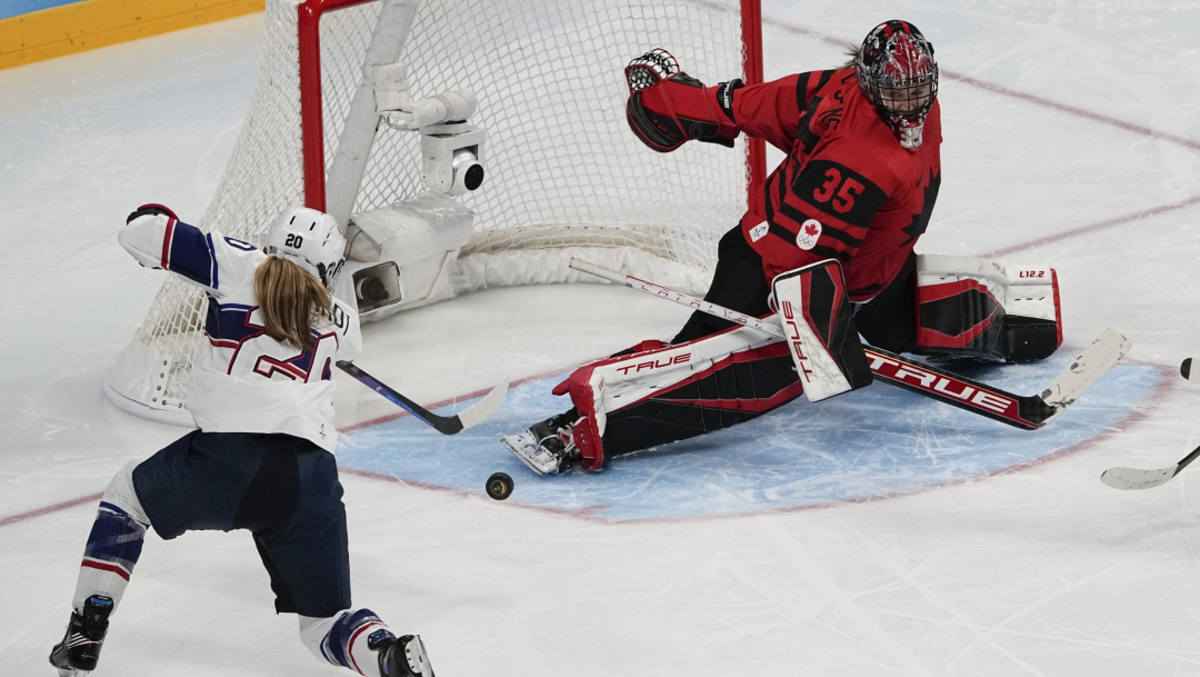 Une gardienne de but effectue un arrêt devant le filet en hockey sur glace