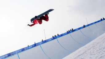Une athlète de snowboard effectue un saut sur la demi-lune