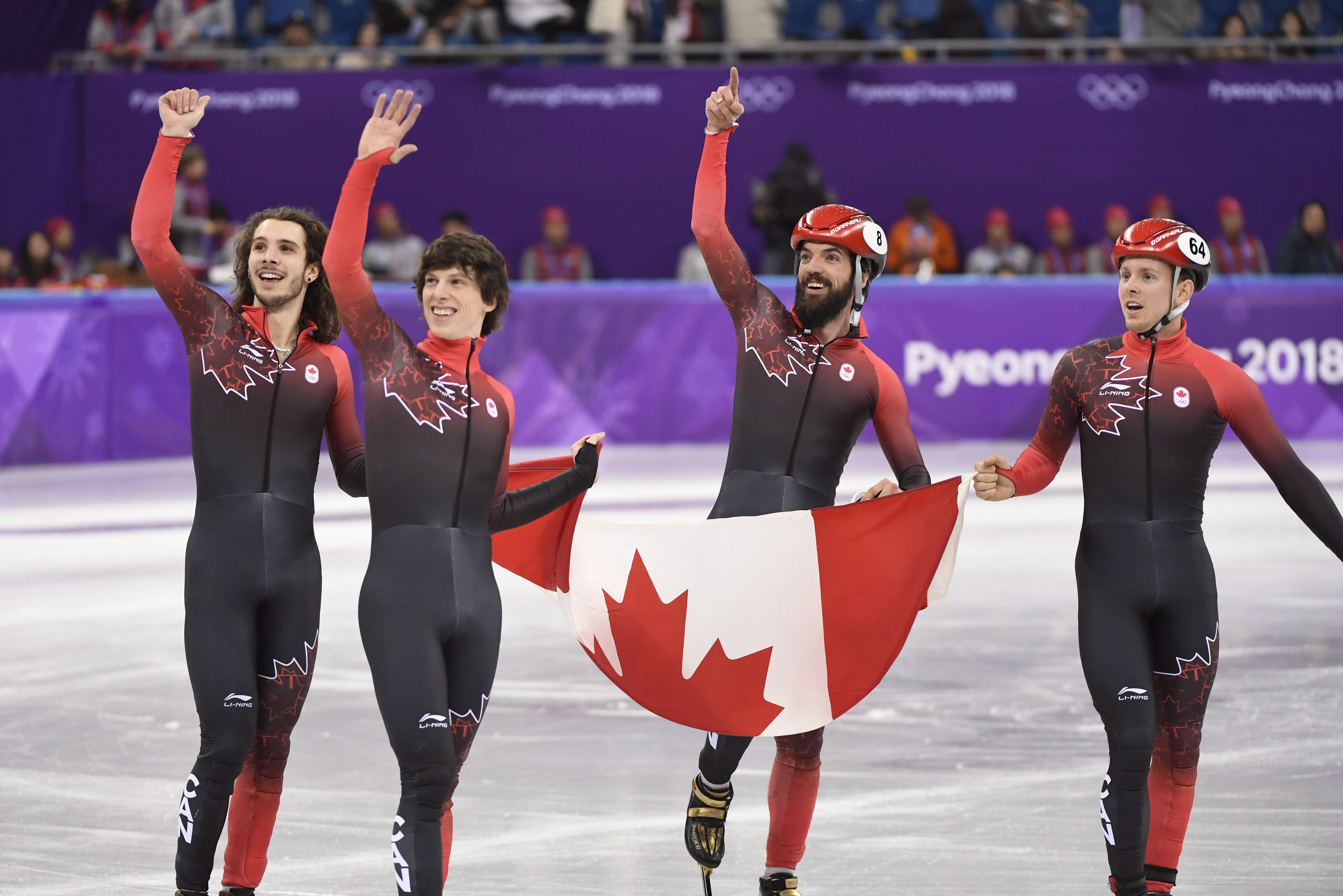 De gauche à droite: Samuel Girard, Charle Cournoyer, Charles Hamelin et Pascal Dion tiennent le drapeau canadien