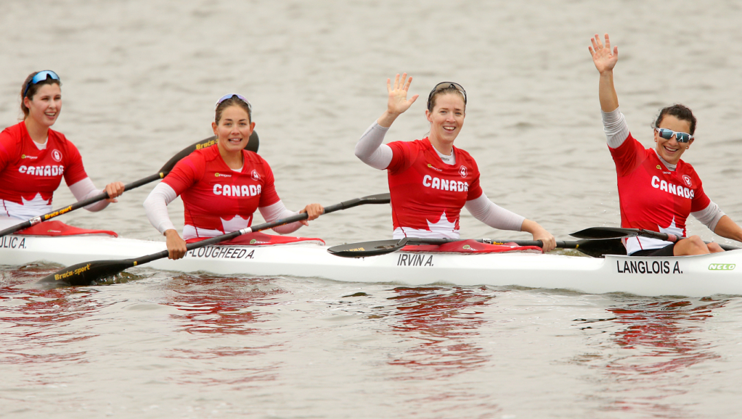 Quatre athlètes saluent la foule de leur kayak