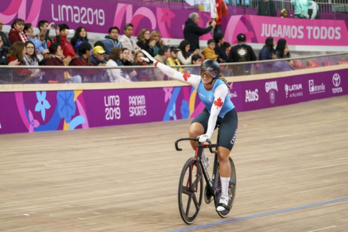 TeamCanadaKelseyMitchellCycling Kelsey Mitchell souriante sur son vélo après avoir remporté une médaille.