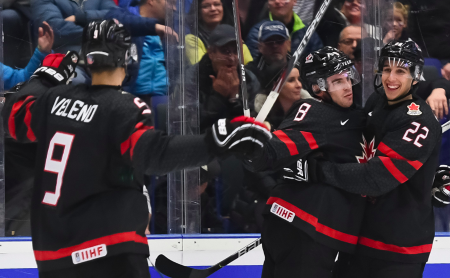 Trois joueurs canadiens célèbrent un but.