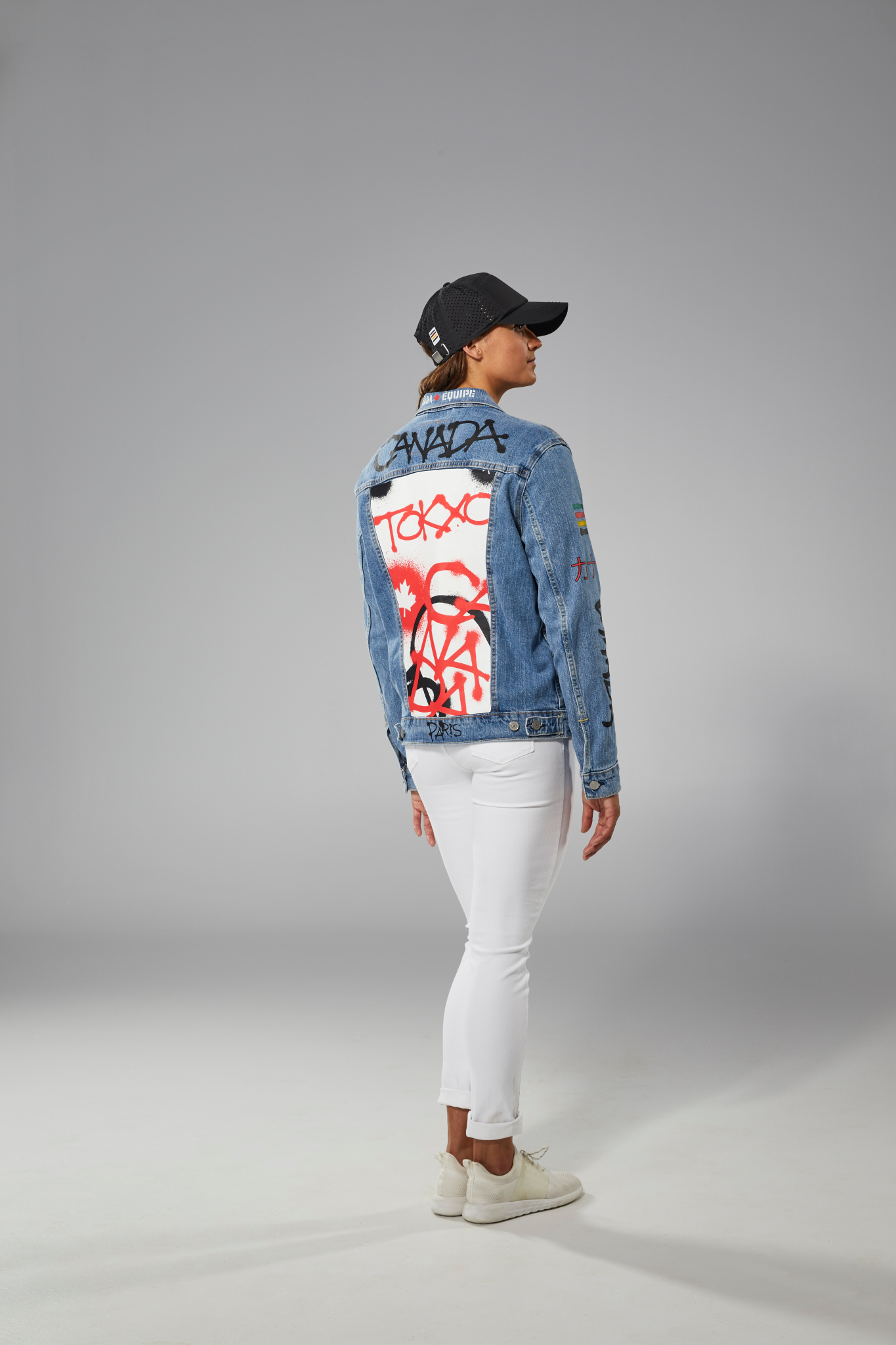 Kylie Masse porte un jeans blanc, un t-shirt noir et une veste en jeans