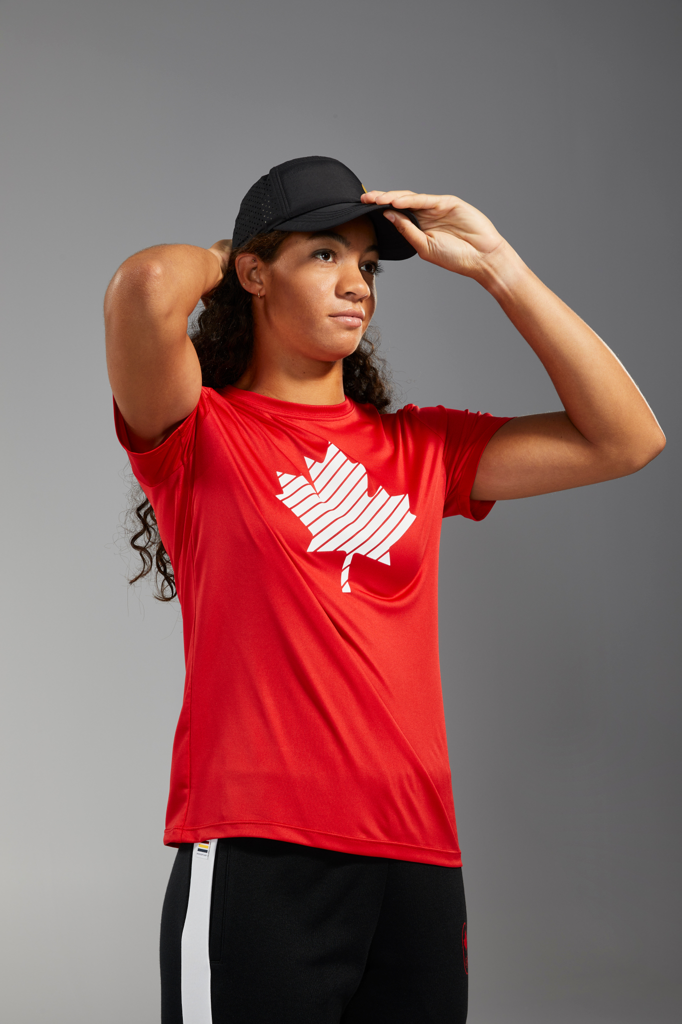 Sarah Douglas porte un t-shirt rouge et une casquette noire