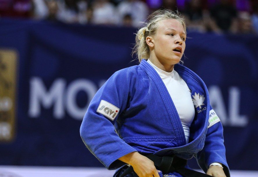 Une judoka resserre sa ceinture noire lors d'un match de judo.