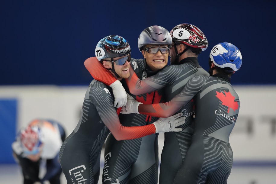 Quatre patineurs de vitesse célèbrent en se serrant.