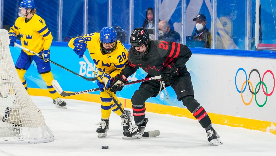 Deux joueuses de hockey sur glace se disputent la rondelle derrière le filet