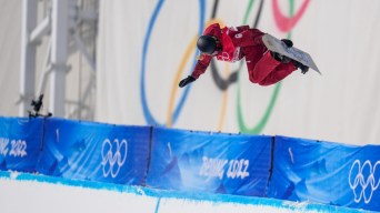 Une athlète de snowboard effectue un saut sur la demi-lune