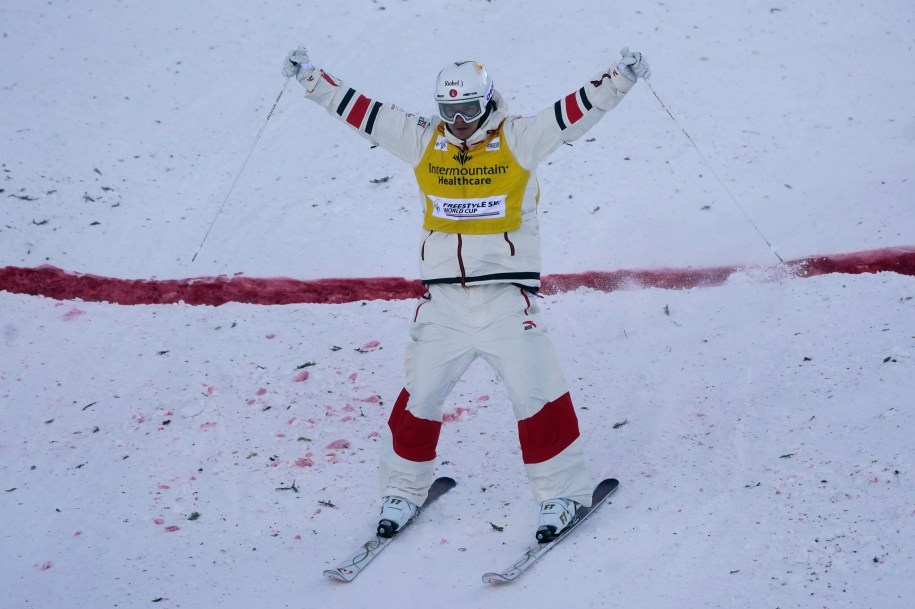 Mikaël Kingsbury lève les bras dans les airs une fois passé la ligne d'arrivée.