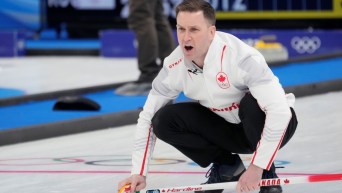 Brad Gushue, accroupi sur la glace, dirige verbalement ses coéquipiers lors du match de curling contre le Comité olympique russe à Beijing 2022