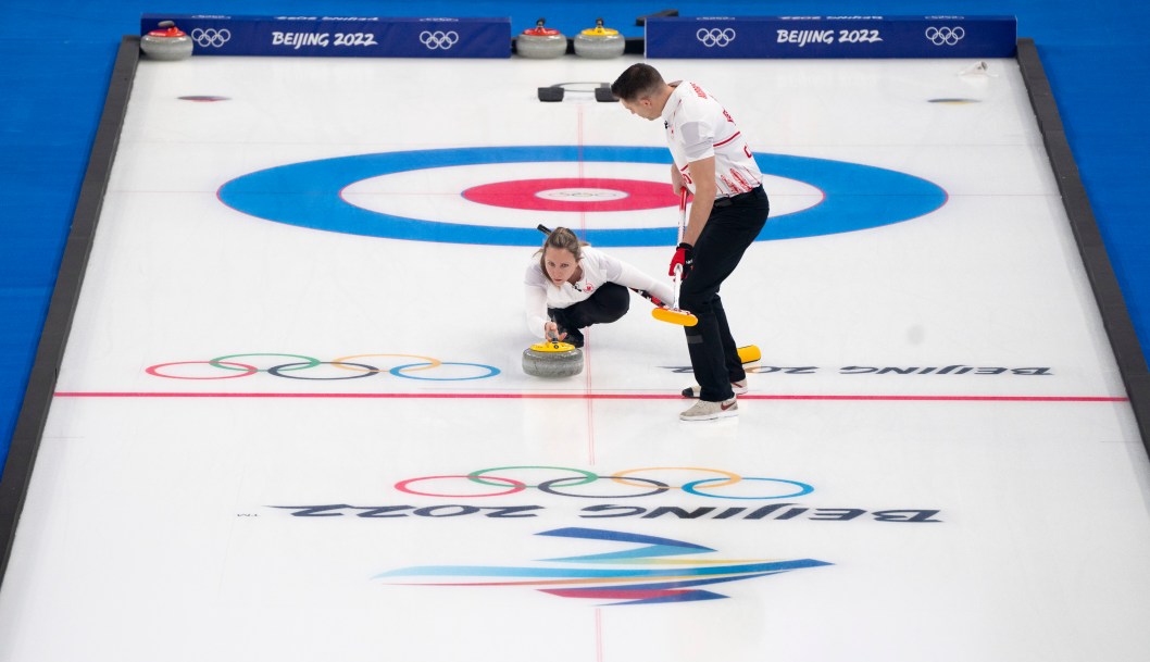 Rachel Homan lance une pierre alors que John Morris s'apprête à balayer la glace