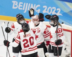 Trois joueuses canadiennes et la gardienne de but célèbrent leur victoire en tapant dans leurs gants.