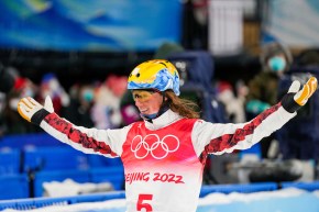 Miha Fontaine célèbre en souriant et levant les mains en l'air après son saut à l'épreuve mixte par équipes du saut acrobatique de Beijing 2022