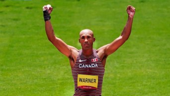 Damian Warner lève les bras dans les airs.