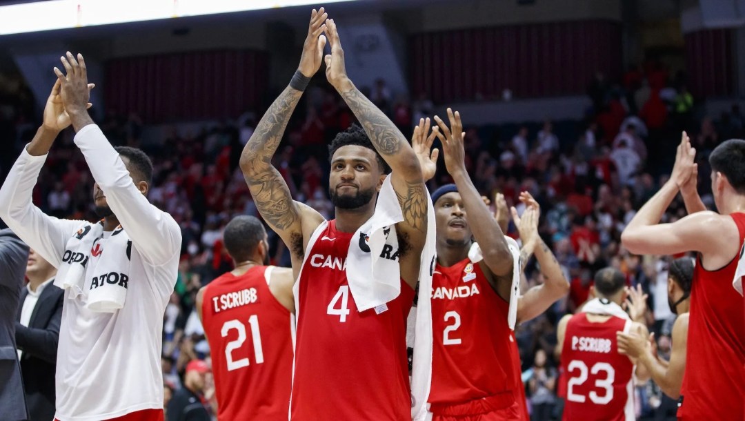 Des joueurs de basketball célèbrent les bras dans les airs.