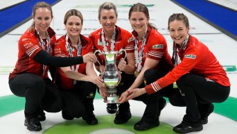 Équipe Homan pose sur la glace avec un imposant trophée.