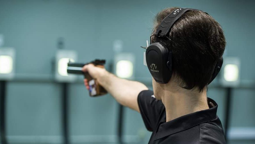 Un homme que l'on voit de dos tient un pistolet.