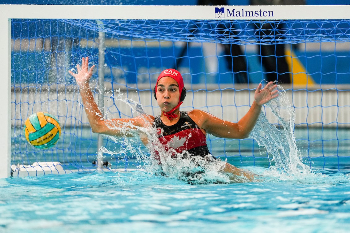 Canadian water polo goaltender puts her arms up to stop the ball 