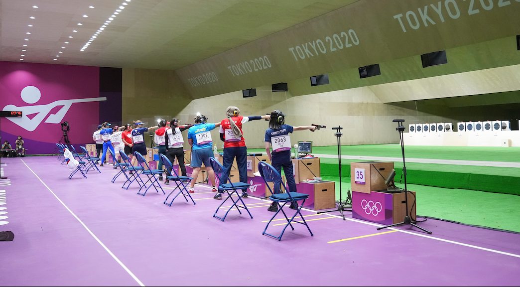 A line of shooters fire their air pistols at targets in a range