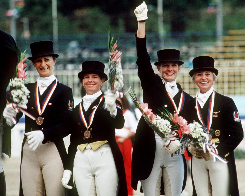 Four Canadian equestrian riders wear their medals on the podium