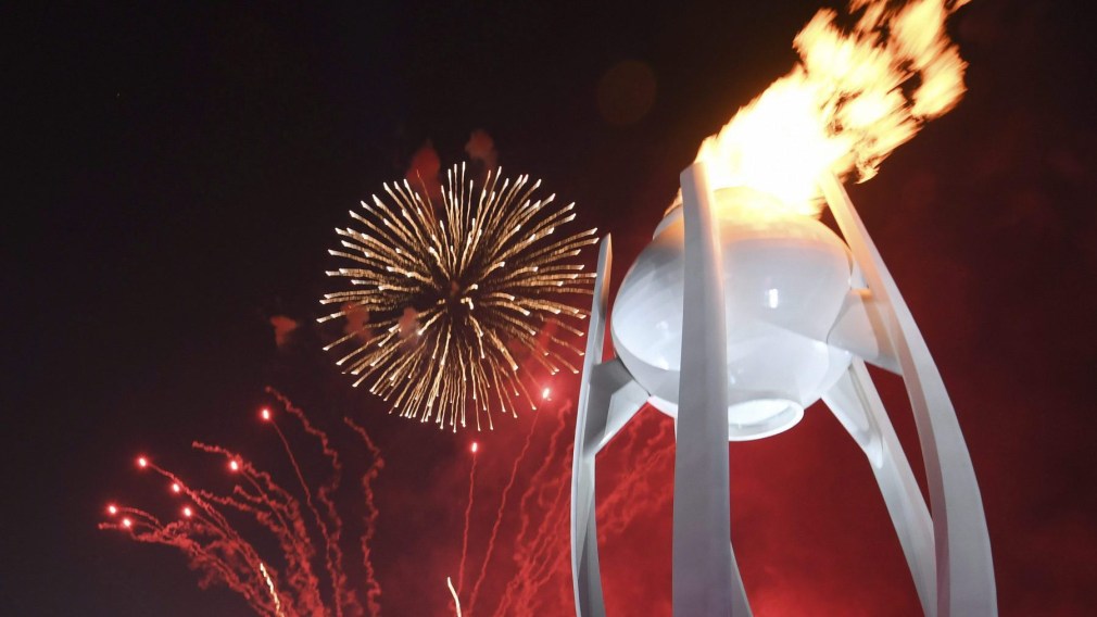 Fireworks explode behind the Olympic flame during the opening ceremony of the 2018 Winter Olympics in Pyeongchang,