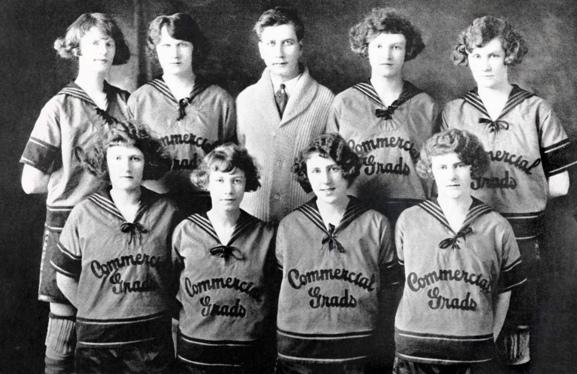Black and white photo of eight women's basketball players and their coach posing for the camera 