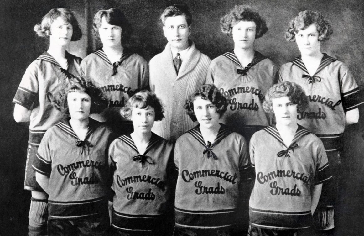 Black and white photo of eight women's basketball players and their coach posing for the camera