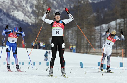 Chandra Crawford (8) of Canmore, Alberta raises her arms to celebrate as she crosses the finish line to win the gold medal women's sprint cross country skiing race at the Olympic Games in Pragelato Plan, Italy on Tuesday, February 22, 2006. Silver medalist Claudia Kuenzel (4) of Germany and bronze medalist Alena Sidko (5) of Russia follow close behind.(CP PHOTO/Frank Gunn)