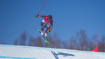 Brady Leman goes over a jump on a ski cross course
