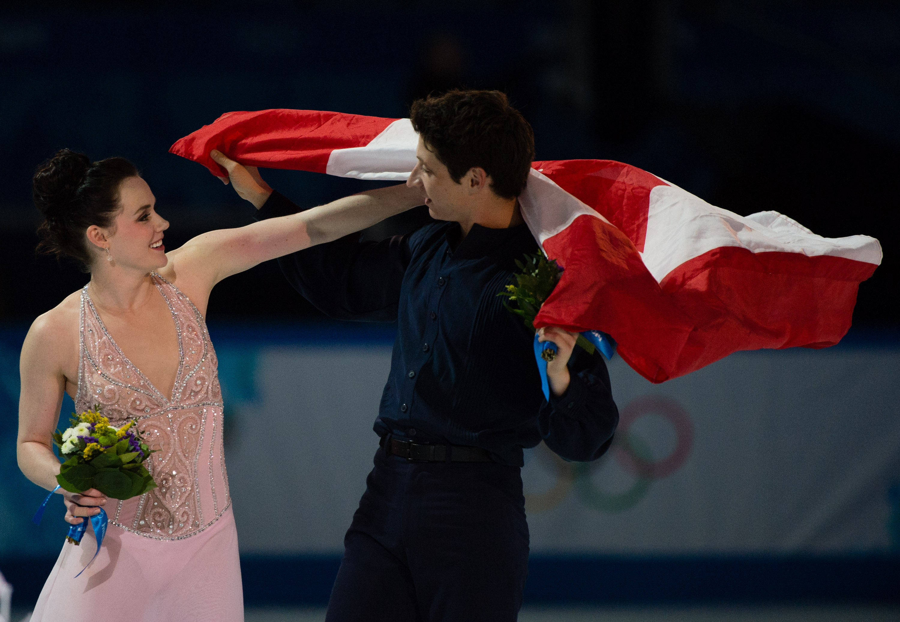 Tessa and Scott celebrating by holding the Canadian flag