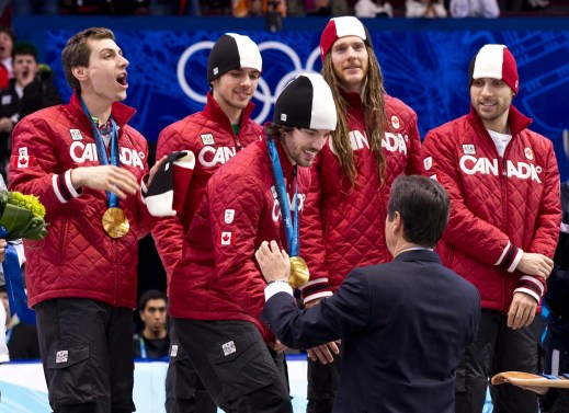 Canada's Charles Hamelin receives his medal as teammates Guillaume Bastille, Francois Hamelin, Olivier Jean and Francois-Louis Tremblay, left to right, look on after winning the gold medal in the men's 5000 metre relay in the short track speedskating competition Friday February 26, 2010 at the Olympic Winter Games in Vancouver. THE CANADIAN PRESS/Paul Chiasson