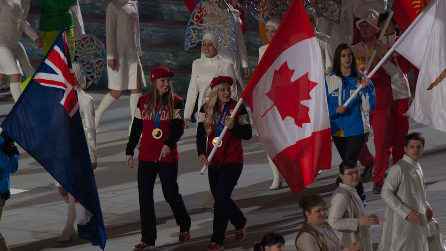 Kaillie Humphries and Heather Moyse carry the flag together at Closing Ceremony of Sochi 2014. 
