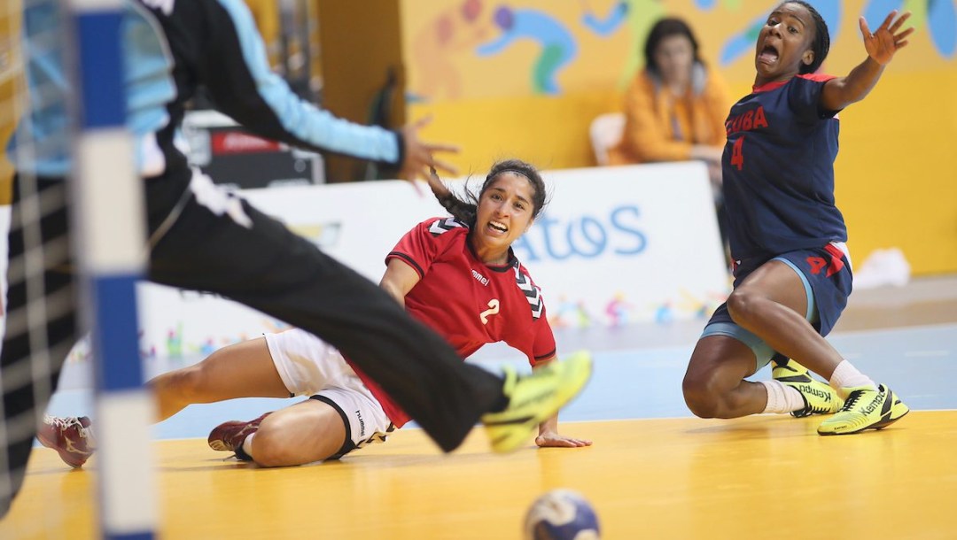 Canadian handball player in red jersey watches her ball roll on the floor to the net