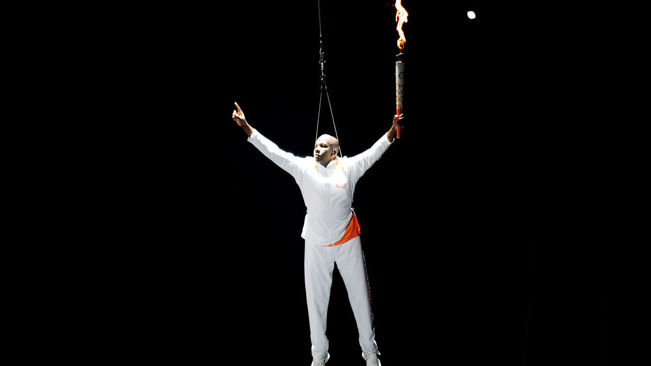 Donovan Bailey is lowered down to the Pan Am Opening Ceremony stage holding the Games' torch on July 10, 2015.