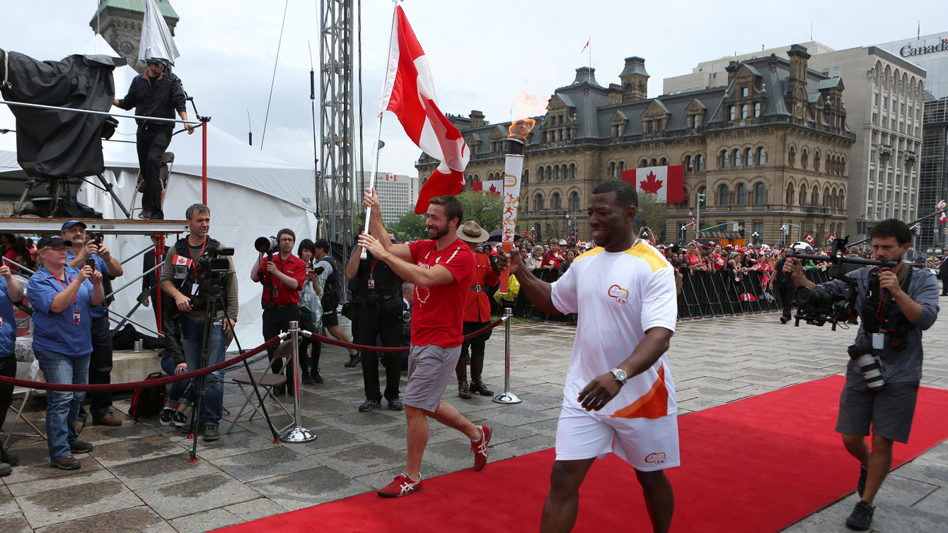 Mark Oldershaw with Olympic 4x100m relay champion from Atlanta 1996, Glenroy Gilbert (carrying the Pan Am Games torch) on the red carpet at Parliament Hill on July 1, 2015 (Greg Kolz for Canadian Olympic Team).