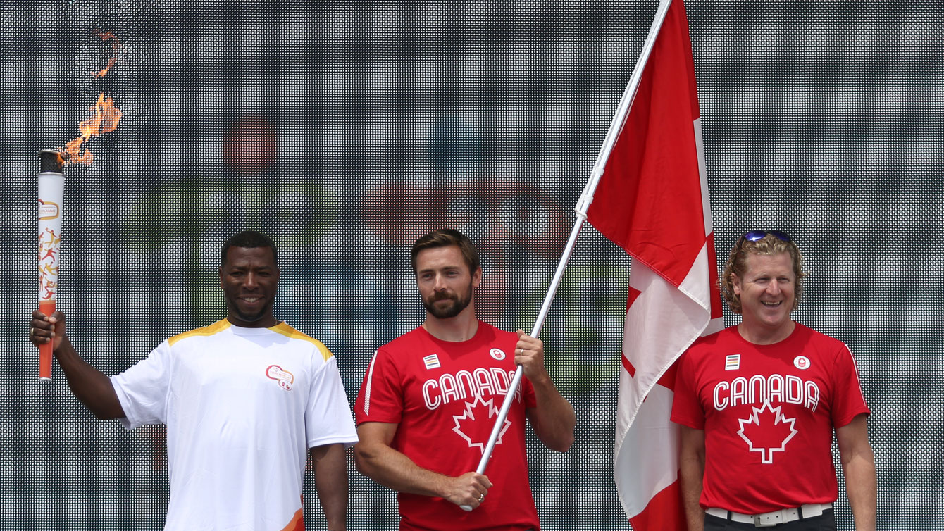 Mark Oldershaw holds the flag flanked by fellow Olympic medallists Glenroy Gilbert (left) and Curt Harnett on stage at Parliament Hill on July 1, 2015 (Greg Kolz for Canadian Olympic Team).