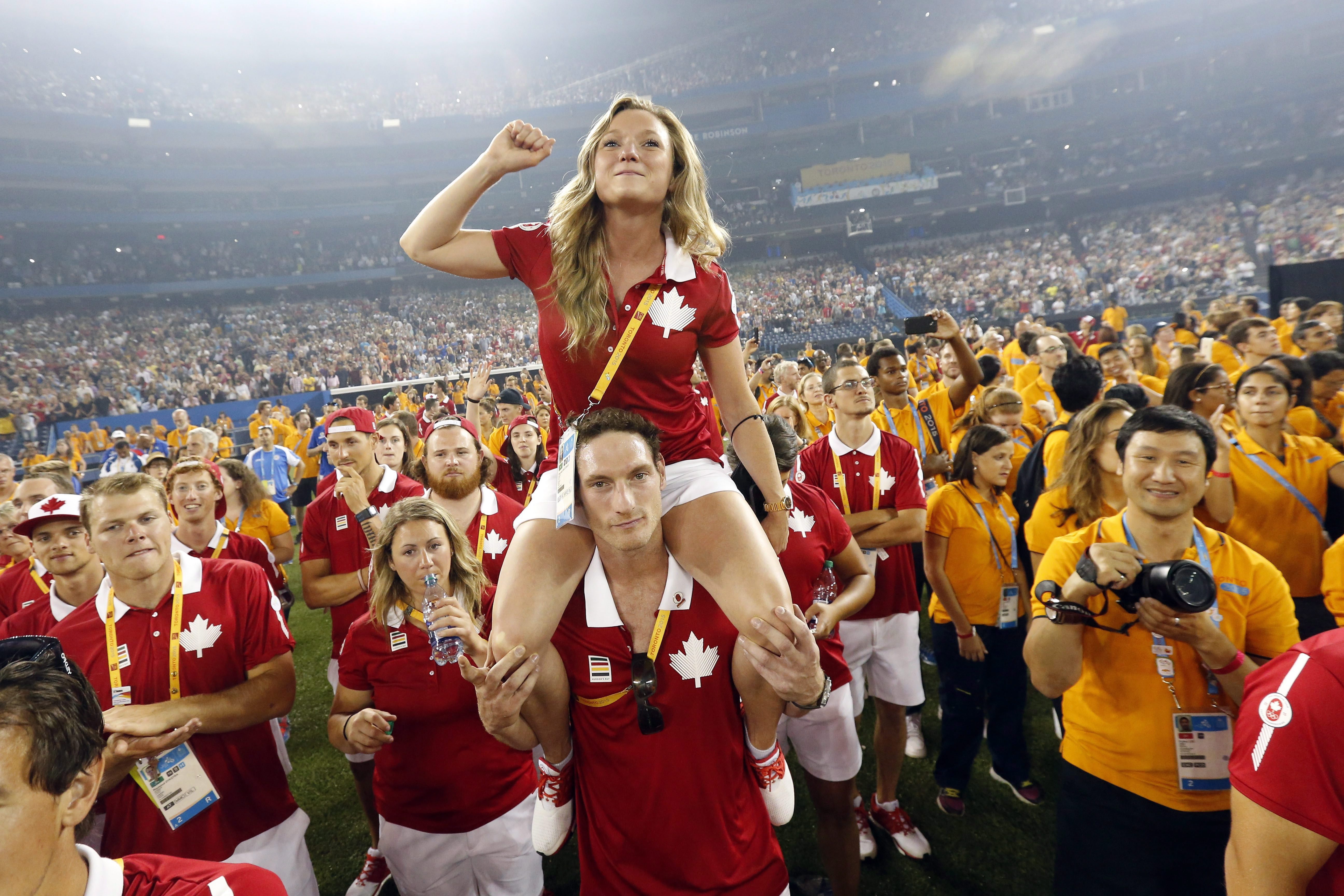 Canadian athletes Rosannagh MacLennan sits on the shoulders of Joshua Binstock as they listen to the entertainment