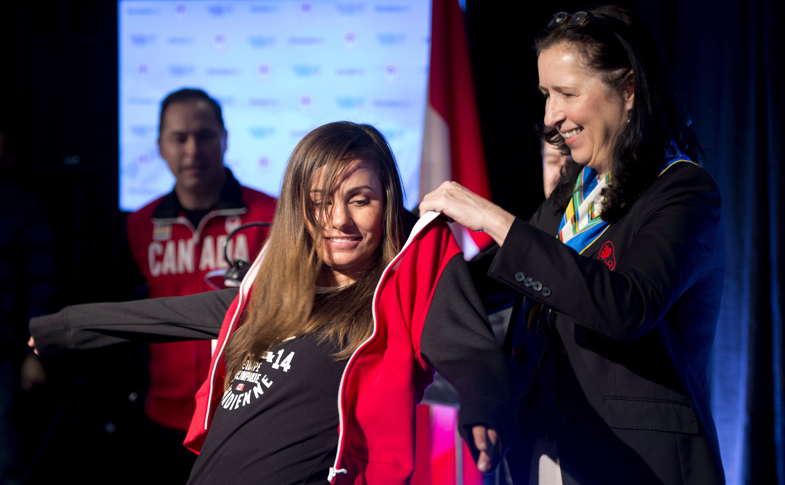 Tricia Smith, vice-president of the Canadian Olympic Committee presents Canadian snowboard team member Maelle Ricker of West Vancouver with her team jacket during the team announcement in Vancouver,Friday, Jan. 3, 2014. THE CANADIAN PRESS/Jonathan Hayward