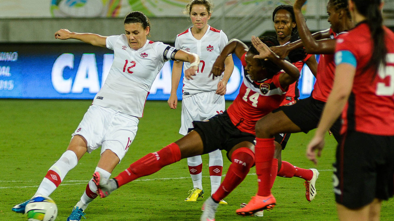 Christine Sinclair (left, in white) sets up to shoot against Trinidad and Tobago on December 13, 2015 at the invitational tournament in Natal. Sinclair scored at the 85th minute to tie Mia Hamm with 158 career goals for second in the all-time list (Photo: Vlademir Alexandre/Allsports). 