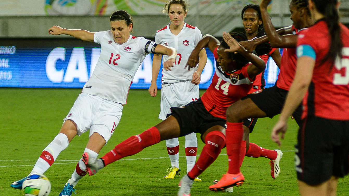 Christine Sinclair (left, in white) sets up to shoot against Trinidad and Tobago on December 13, 2015 at the invitational tournament in Natal. Sinclair scored at the 85th minute to tie Mia Hamm with 158 career goals for second in the all-time list (Photo: Vlademir Alexandre/Allsports).
