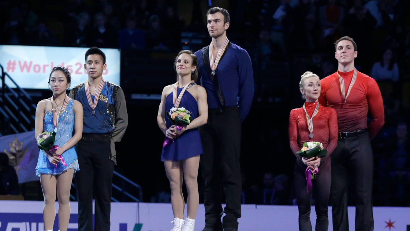 Meagan Duhamel and Eric Radford (centre) stand atop the pairs gold medal spot at the ISU Speed Skating World Championships podium ceremony on April 2, 2016.