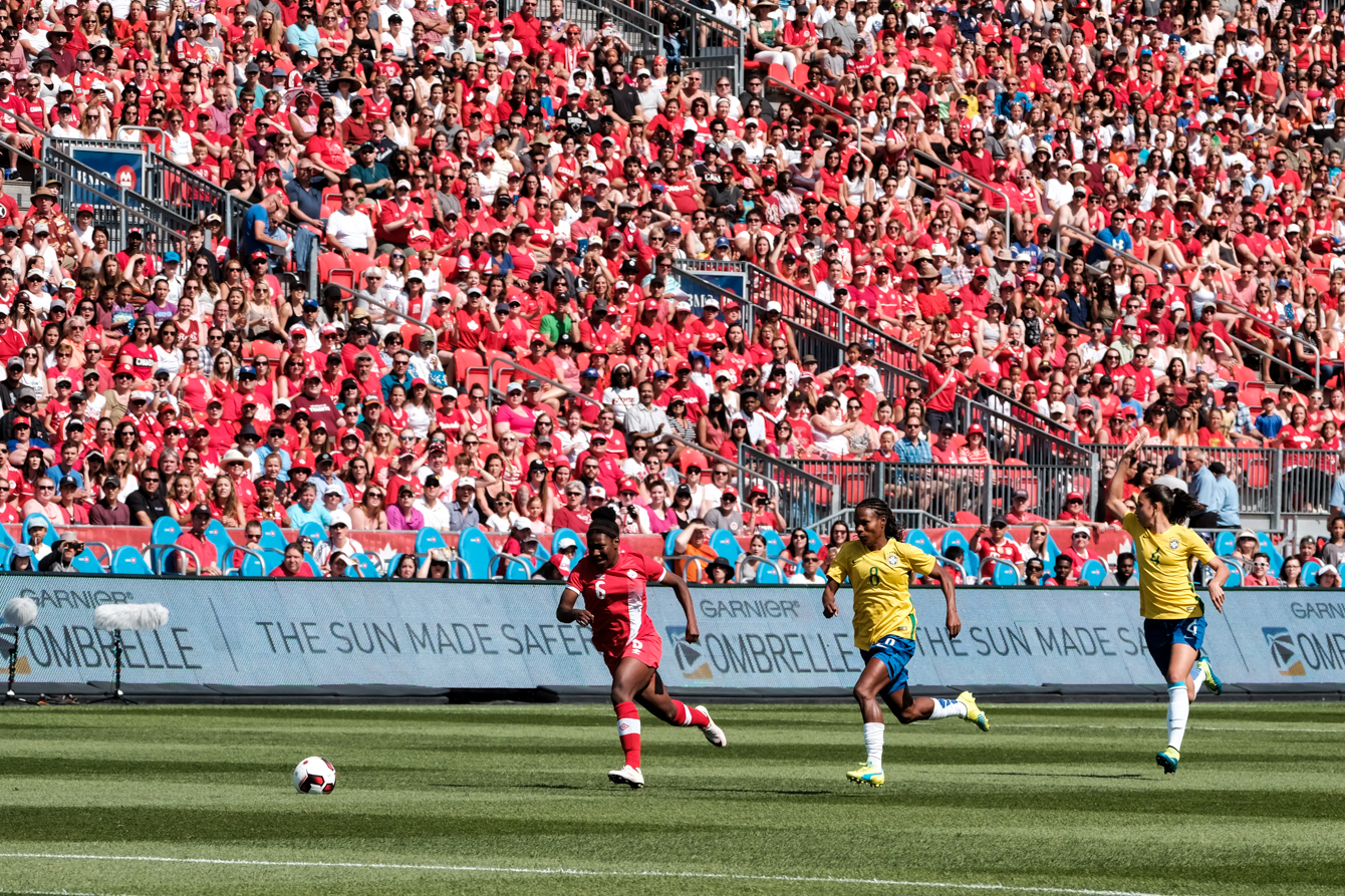 A Team Canada player running with the ball while a Brazilian player tries to catch up
