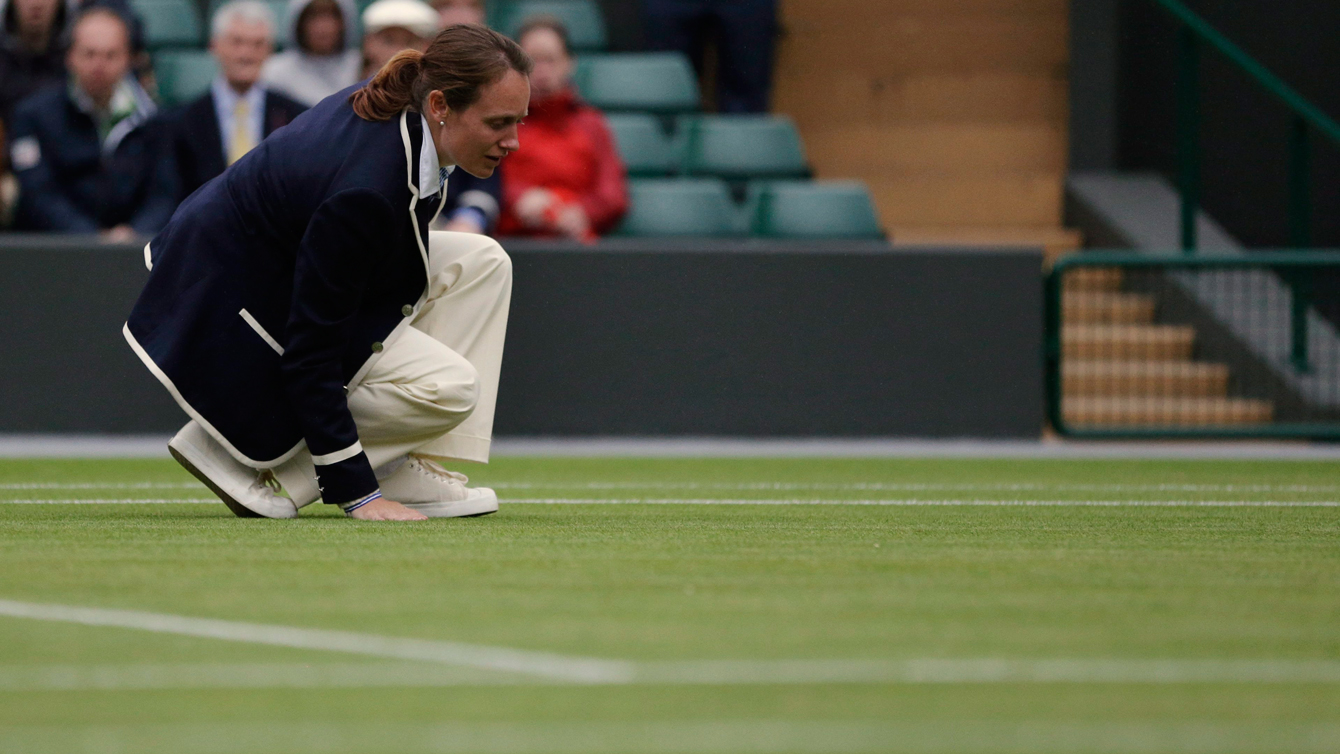 An official feels the grass as Agnieszka Radwanska of Poland and Maria Kirilenko of Russia play a quarterfinals match at the All England Lawn Tennis Championships at Wimbledon, England, Tuesday, July 3, 2012. (AP Photo/Kirsty Wigglesworth)