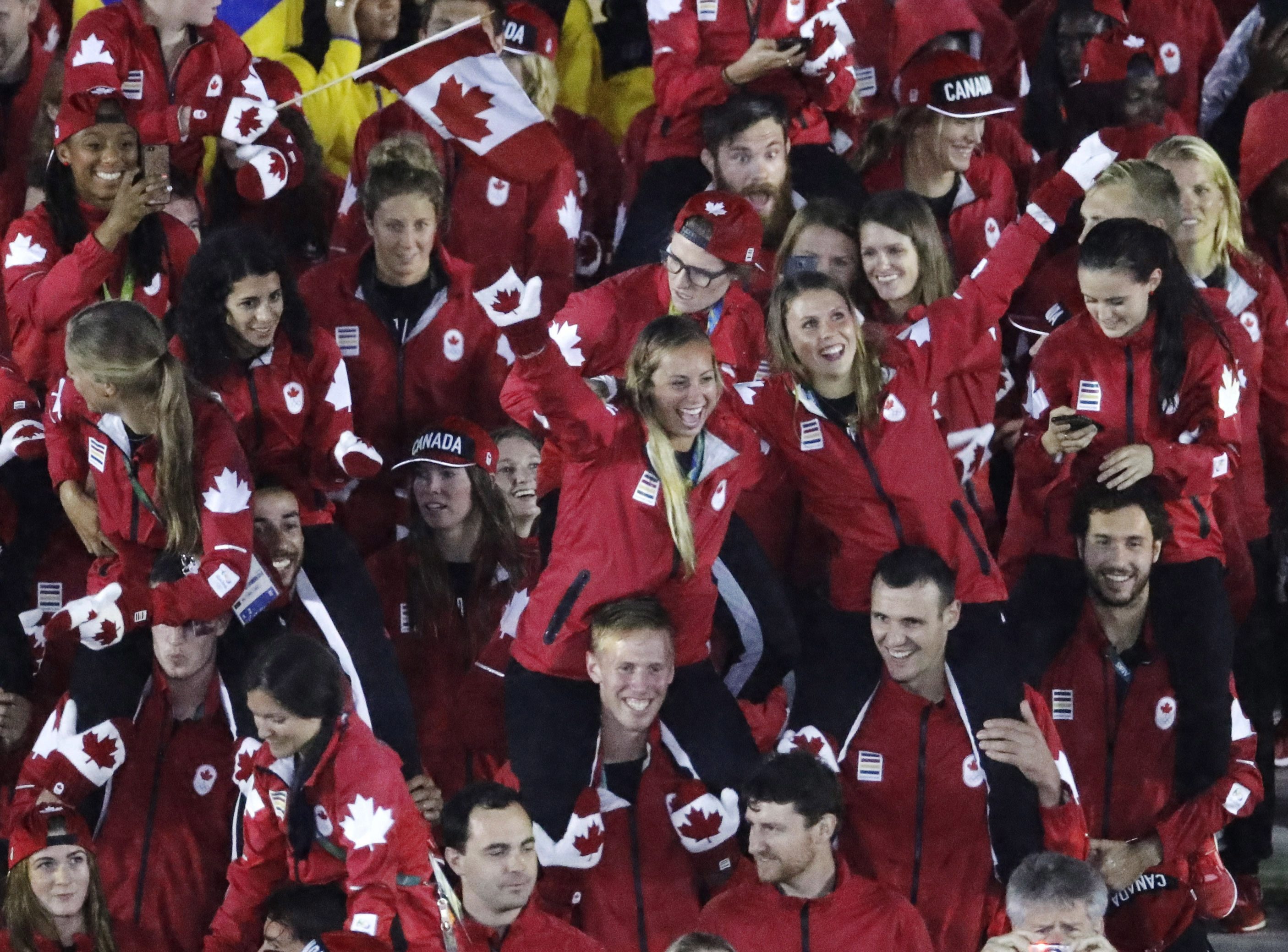 Athetes from Canada, some wearing mittens, march into the closing ceremony in the Maracana stadium at the 2016 Summer Olympics in Rio de Janeiro, Brazil, Sunday, Aug. 21, 2016. (AP Photo/Charlie Riedel)