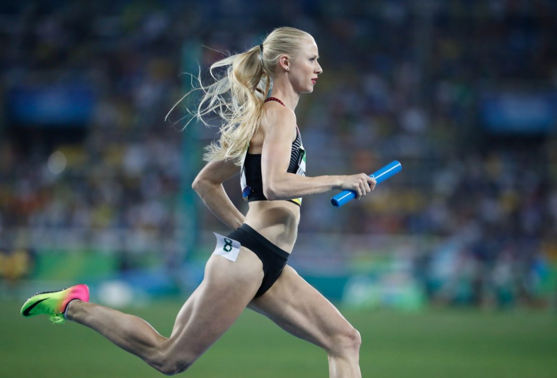 Sage Watson running on the track with the baton